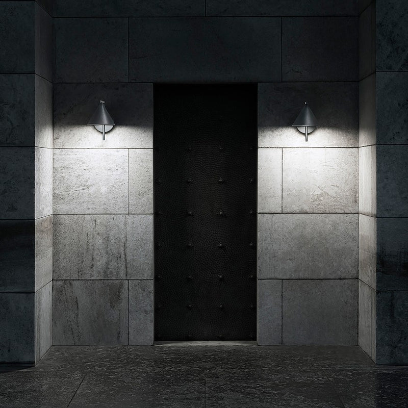 Two Flos Captain Flint Outdoor wall sconces flank a dark doorway from a stone wall.