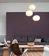 Three Flos Glo-Ball suspension lamps hanging in a group above a furnished living room.