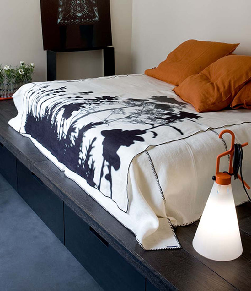 Flos Mayday Utility Lamp next to a bed on a wooden floor.