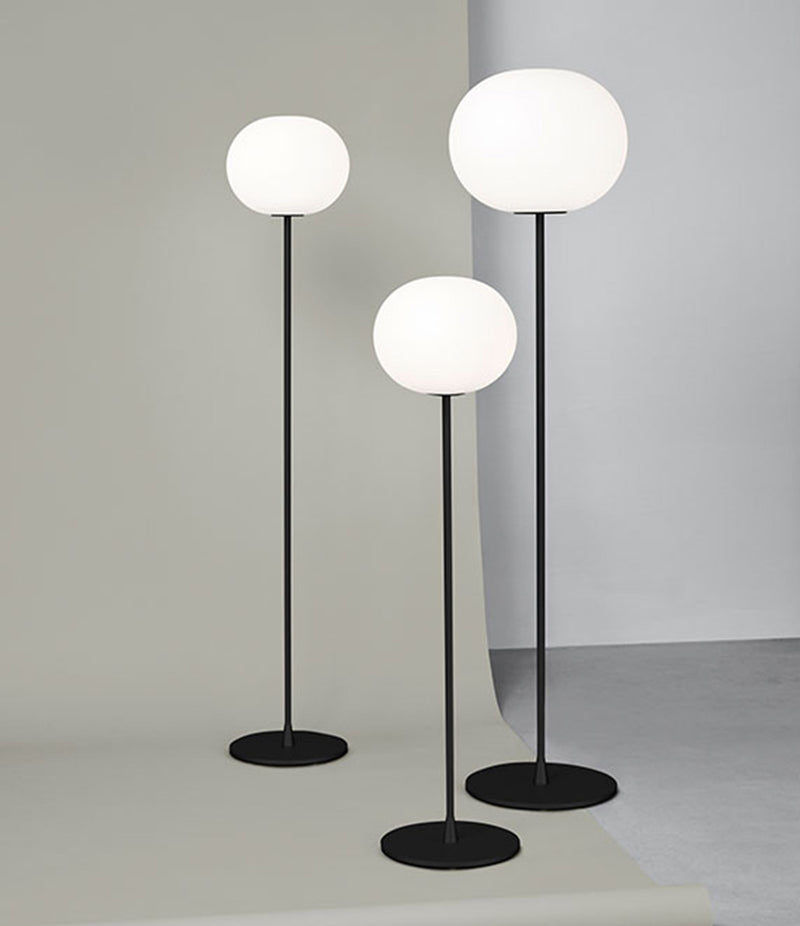Small, medium and large Flos Glo-Ball floor lamps standing in a group.