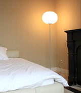 Flos Glo-Ball Floor Lamp in matte silver next to a bed.