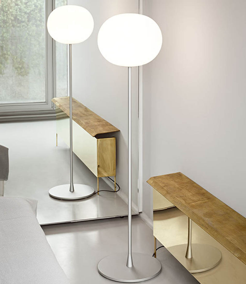 Flos Glo-Ball floor lamp in matte silver stands in front of a mirror.