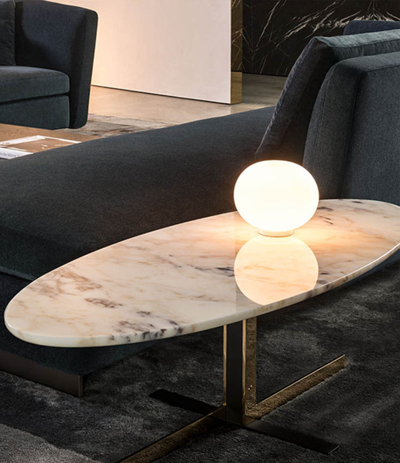 Flos Glo-Ball Basic Zero table lamp on a marble coffee table next to a sofa.