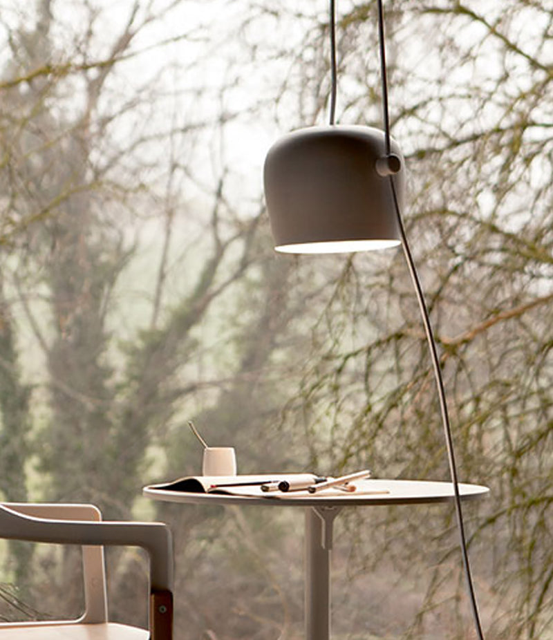 Flos Aim suspension lamp hangs above small wooden table and chair.