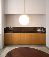 Brass Flos IC Lights suspension lamp hanging above a wooden table in a dining room.