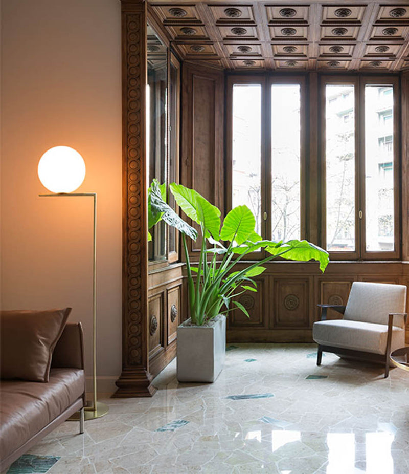 Flos IC Lights Floor Lamp in wood-panelled living room next to leather sofa.