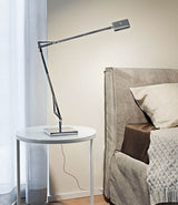 Flos Kelvin Edge table lamp, with double-jointed stem and flat multi-directional LED head, on a bedside table.