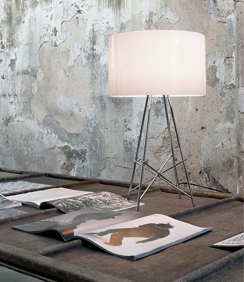 Flos Ray table lamp on a table next to open magazines.