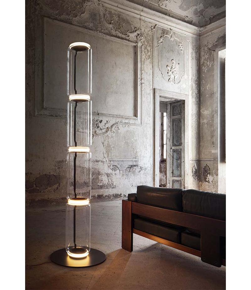 Flos Noctambule floor lamp in a large room with venetian plaster walls. 4 glass cylinders with circular steel base.