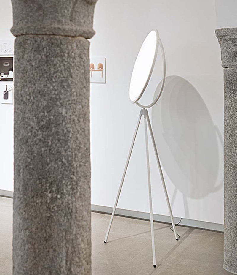 Flos Superloon floor lamp standing against a wall next to stone pillars.
