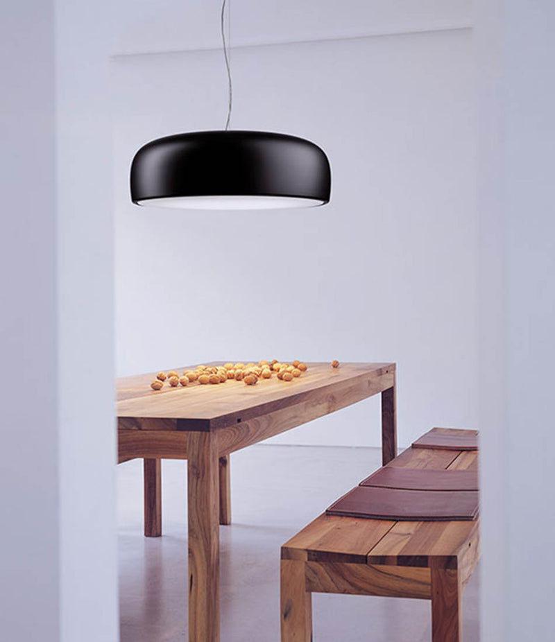 Flos Smithfield pendant lamp hanging above a wooden table and bench.