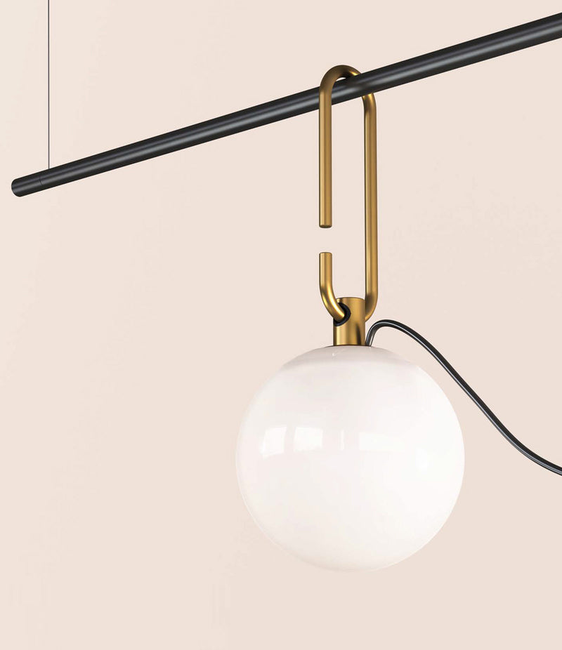Glass globe diffuser of Artemide NH S1 suspension lamp hangs from horizontal bar by oval hook system.