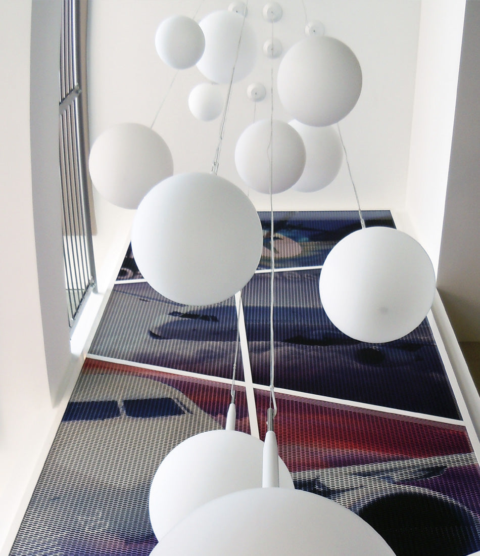 A group of Artemide Castore Suspension lamps above a carpeted hallway.