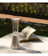 Artemide Come Together portable table lamp on an outdoor table beside a book.