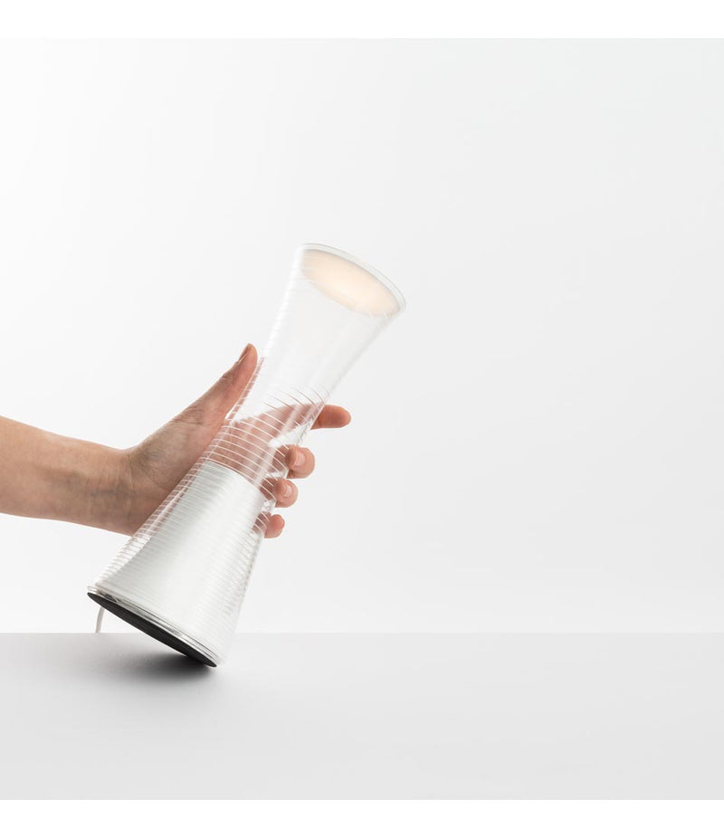 A hand grips an Artemide Come Together portable table lamp.