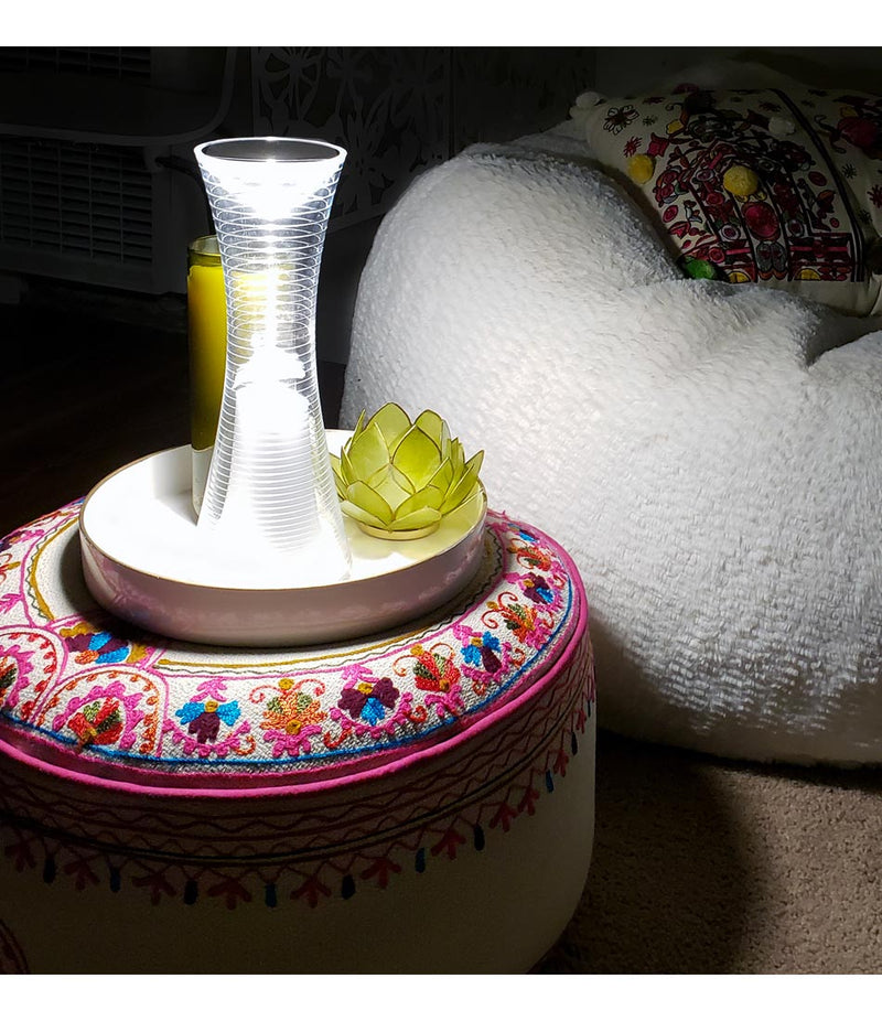 Artemide Come Together table lamp in a ceramic plate on an embroidered ottoman.