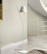 White Artemide La Petite floor lamp on a concrete floor near a curved staircase.