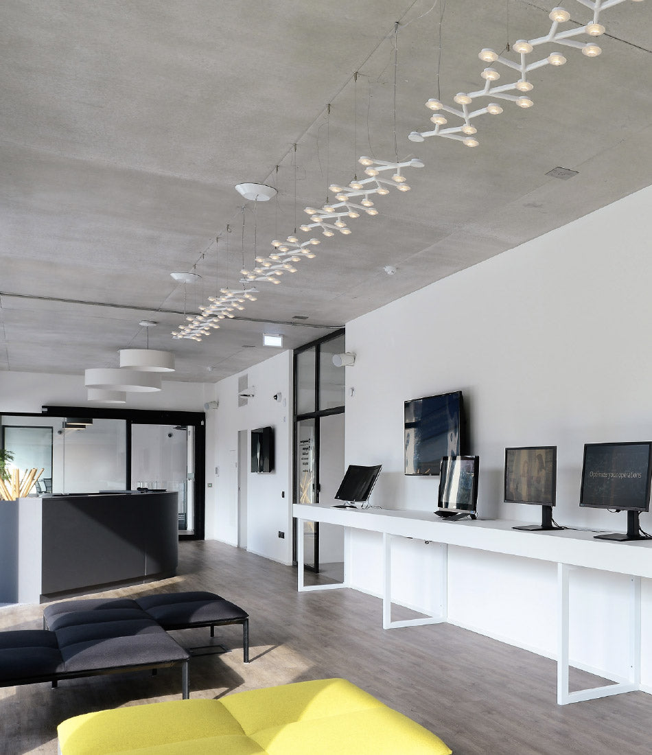 Three Artemide Led Net Line 125 suspension lamps mounted in line above an office.