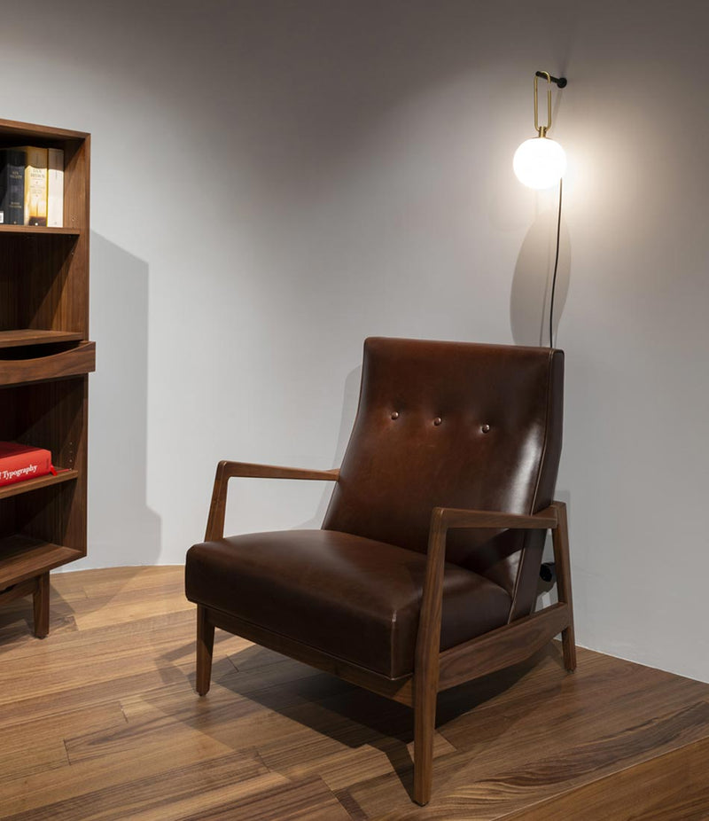 Artemide NH Wall Lamp hangs above a leather armchair.