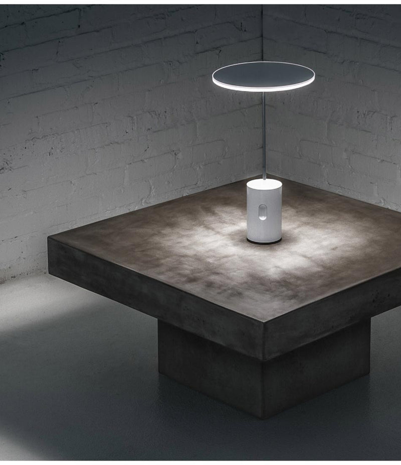Artemide Sisifo table lamp on a thick square tabletop.