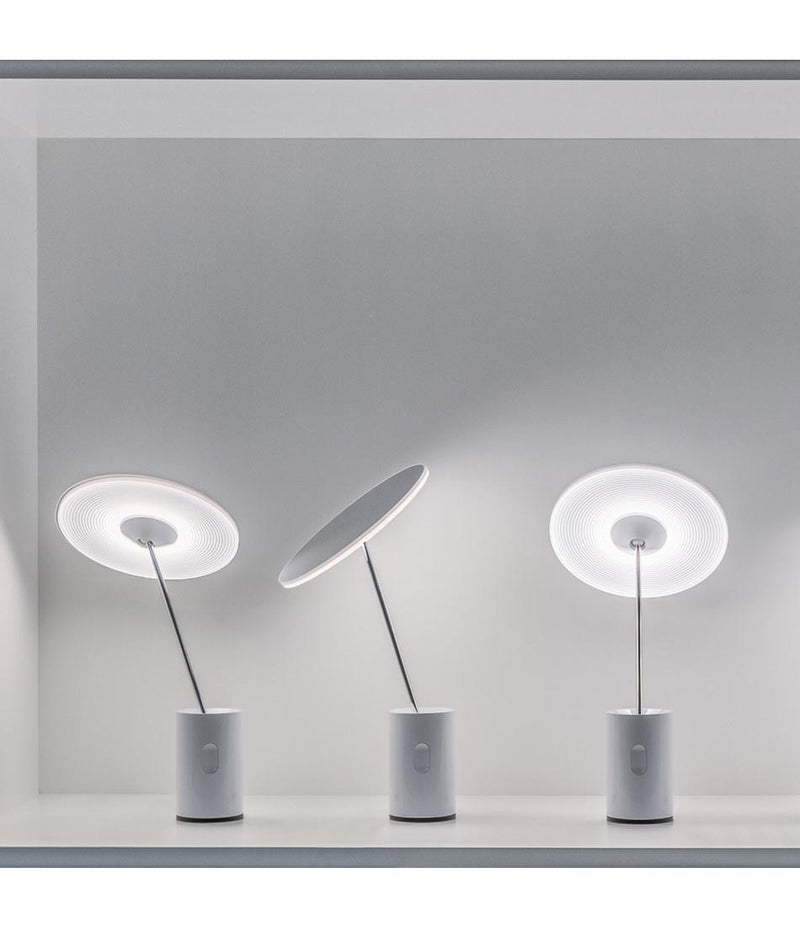 Three Artemide Sisifo table lamps in a row, stems and diffusers tilted in different directions.