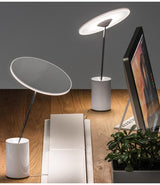 Two Artemide Sisifo table lamps on a wooden desktop, next to a computer.