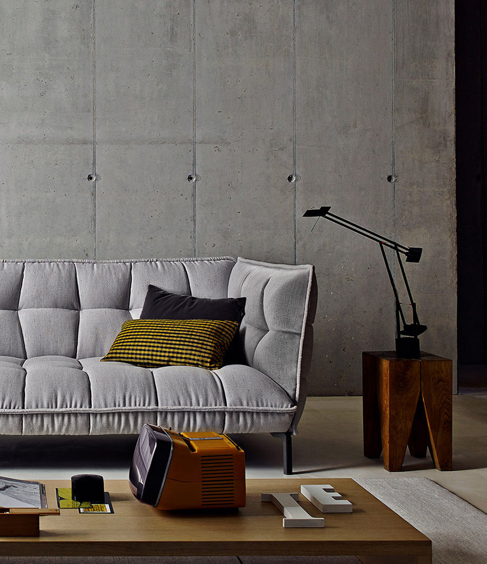 Artemide Tizio table lamp on a wooden side table next to a sofa, in a living room.
