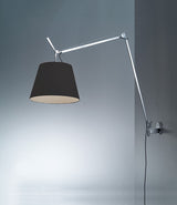 Artemide Tolomeo Mega wall lamp mounted to a wall, with aluminum arm and black lampshade.