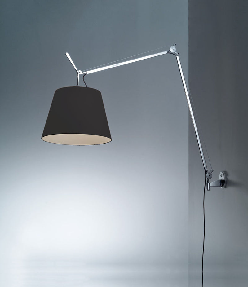 Artemide Tolomeo Mega wall lamp mounted to a wall, with aluminum arm and black lampshade.
