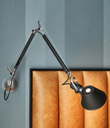 Black Artemide Tolomeo wall lamp with J-bracket mounted next to a leather headboard.