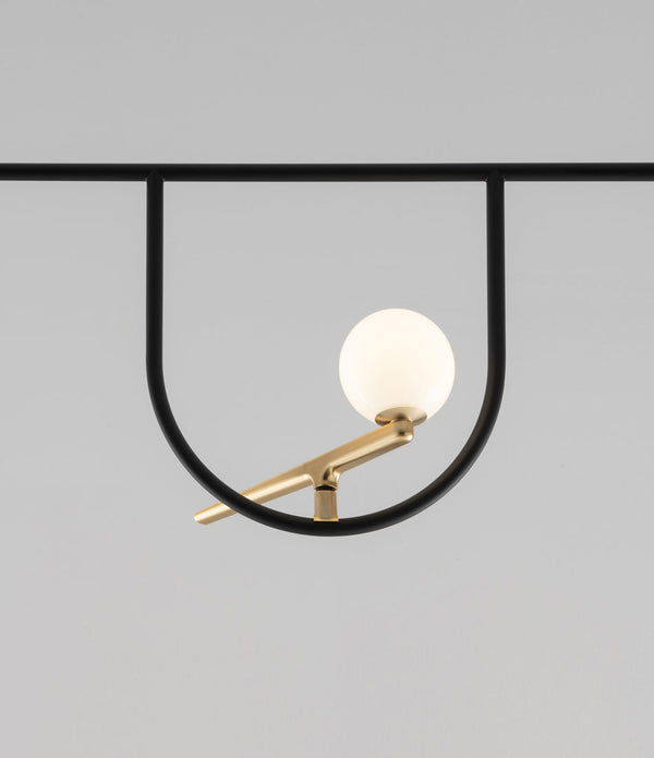 Close-up of bird-shaped light perched in U-shaped structure of Artemide Yanzi SC1 suspension lamp.