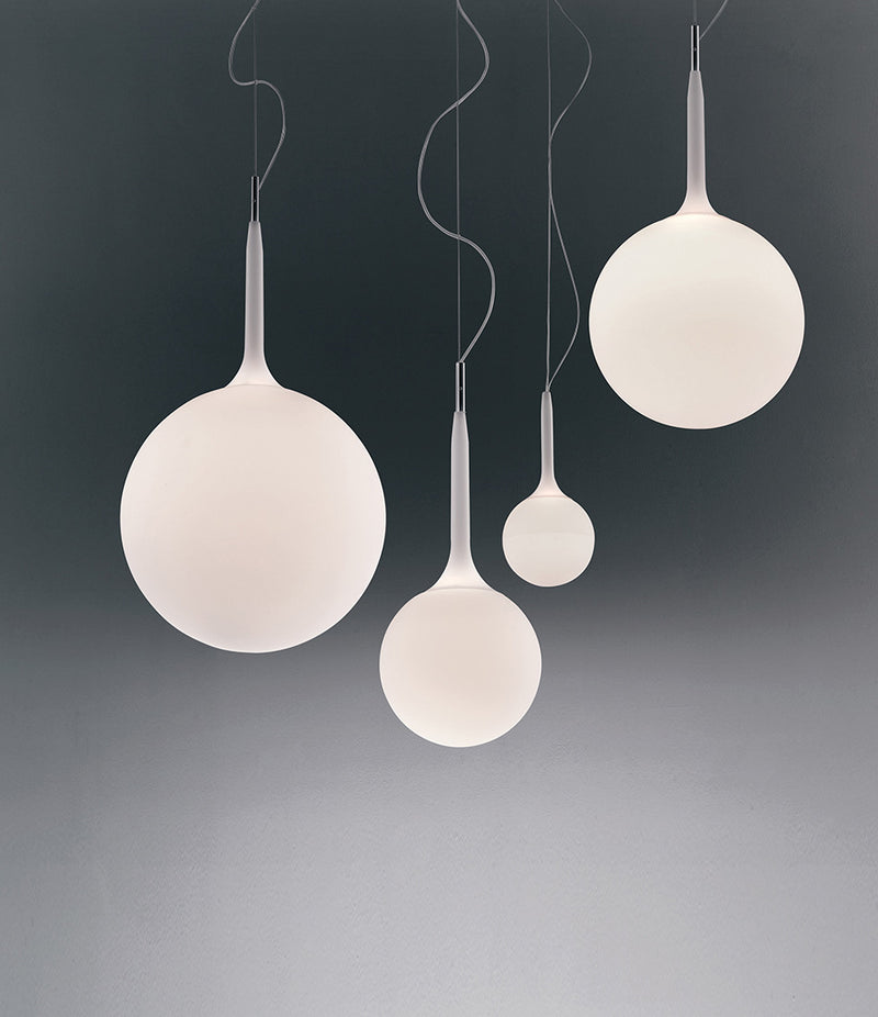 A group of Artemide Castore Suspension Lamps hanging in front of a dark background.