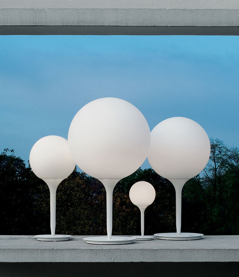 Four Artemide Castore table lamps on a concrete window sill.