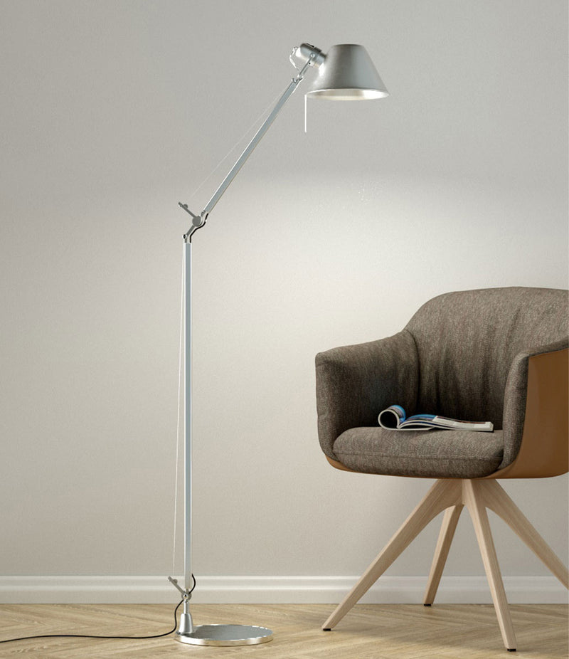 Artemide Tolomeo Reading floor lamp in aluminum finish beside a lounge chair.