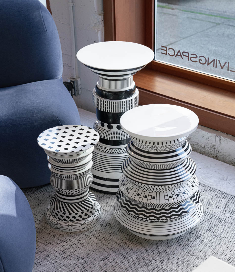 "Regina", "Vinicius" and "Gilberto" side tables clustered on a carpet next to a lounge chair.