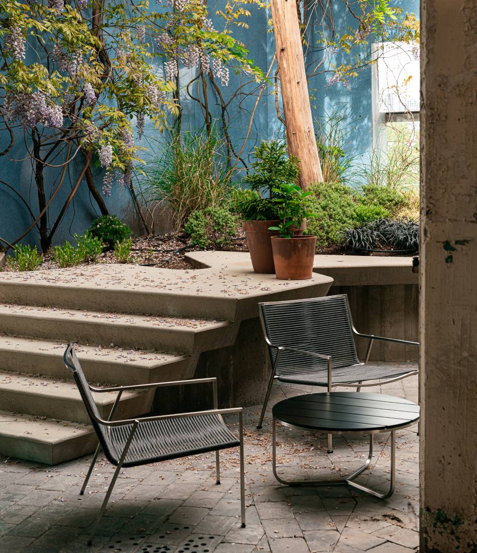 Coro SG1 coffee table next to two lounge chairs in an outdoor courtyard.