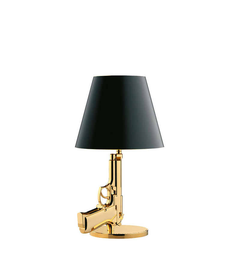 Flos Guns Bedside table lamp, with stem in the shape of a gold pistol and black lampshade.