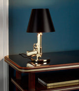 Flos Guns Bedside Table Lamp on a wood sideboard.