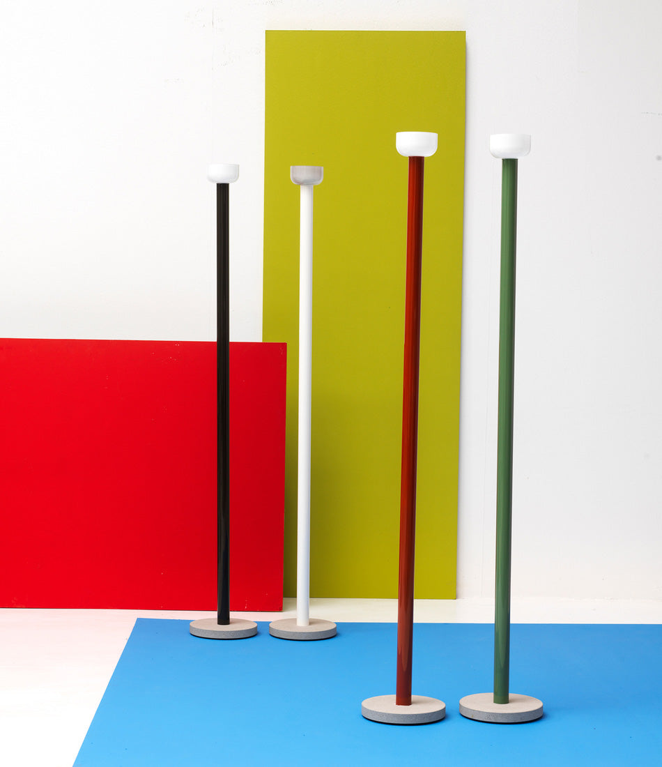 Black, white, brick red and green Flos Bellhop floor lamps standing in a group in a multi-coloured room.