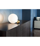 Flos Copycat table lamp on a black drawer chest against a blue wall.