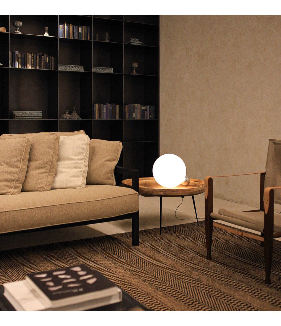 Flos Copycat table lamp on a wooden end table, beside a sofa and lounge chair.