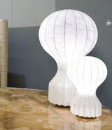 A small and large Flos Gatto table lamp side by side on stone tabletop.