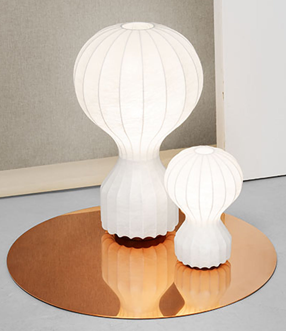 A small and large Gatto table lamp on a flat circular copper disc.