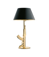 Flos Guns Table Lamp, with gold stem in the shape of an ak-47 assault rifle. Black lampshade.
