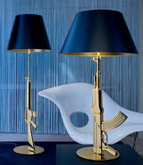 Two Flos Guns Table Lamps on a coffee table next to a lounge chair.