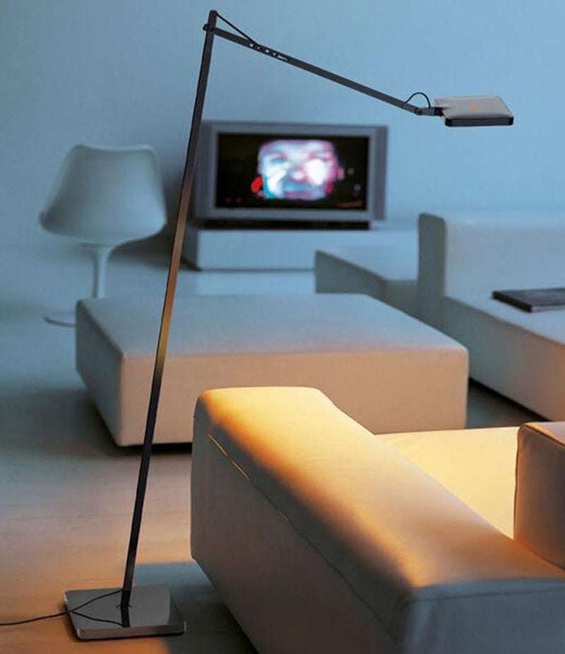 Flos Kelvin Edge LED floor lamp, with elbowed stem and multi-directional head beside a sofa in a living room.