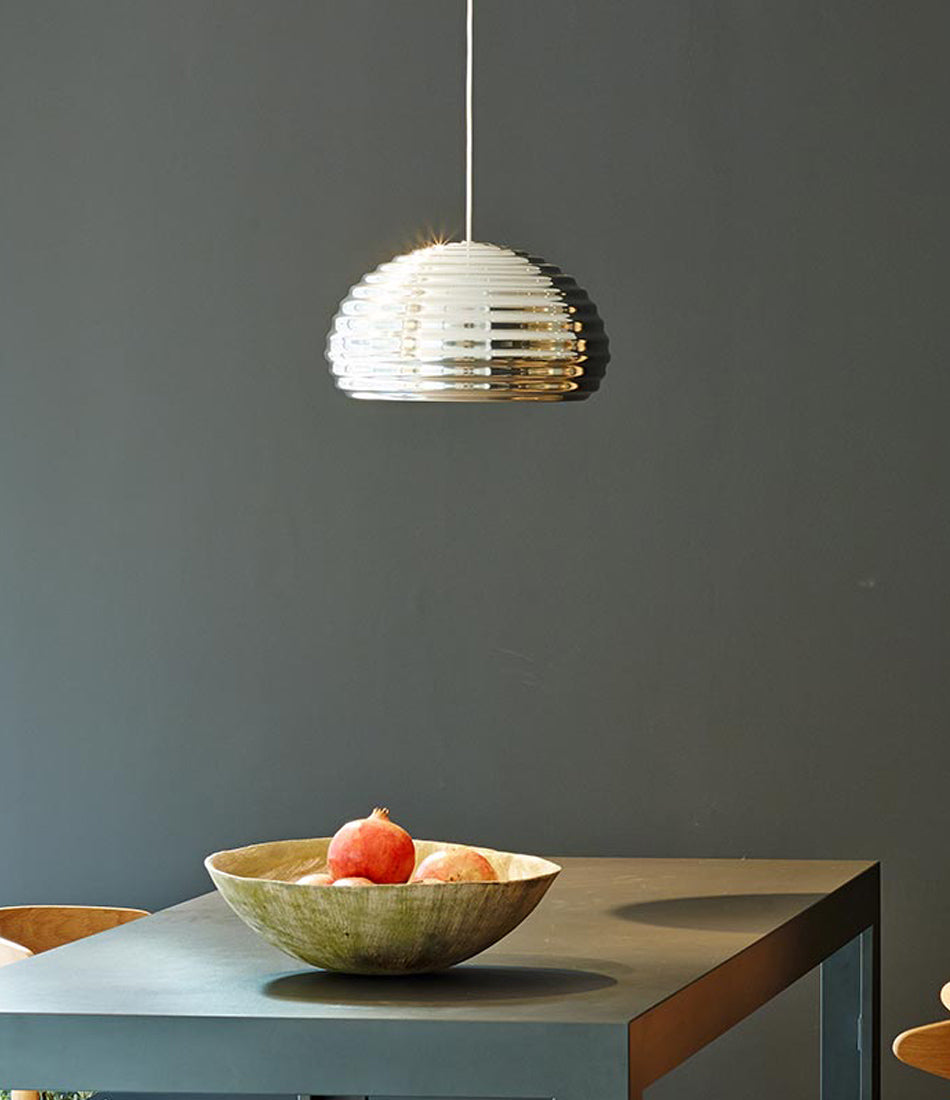 Flos Splugen Brau ceiling lamp above a fruit bowl on a dining table.
