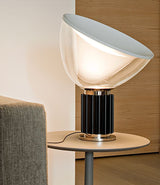 Flos Taccia table lamp on a side table beside a sofa.