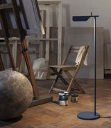 Flos Tab floor lamp in an artist studio, next to a can of paint and wooden stool.