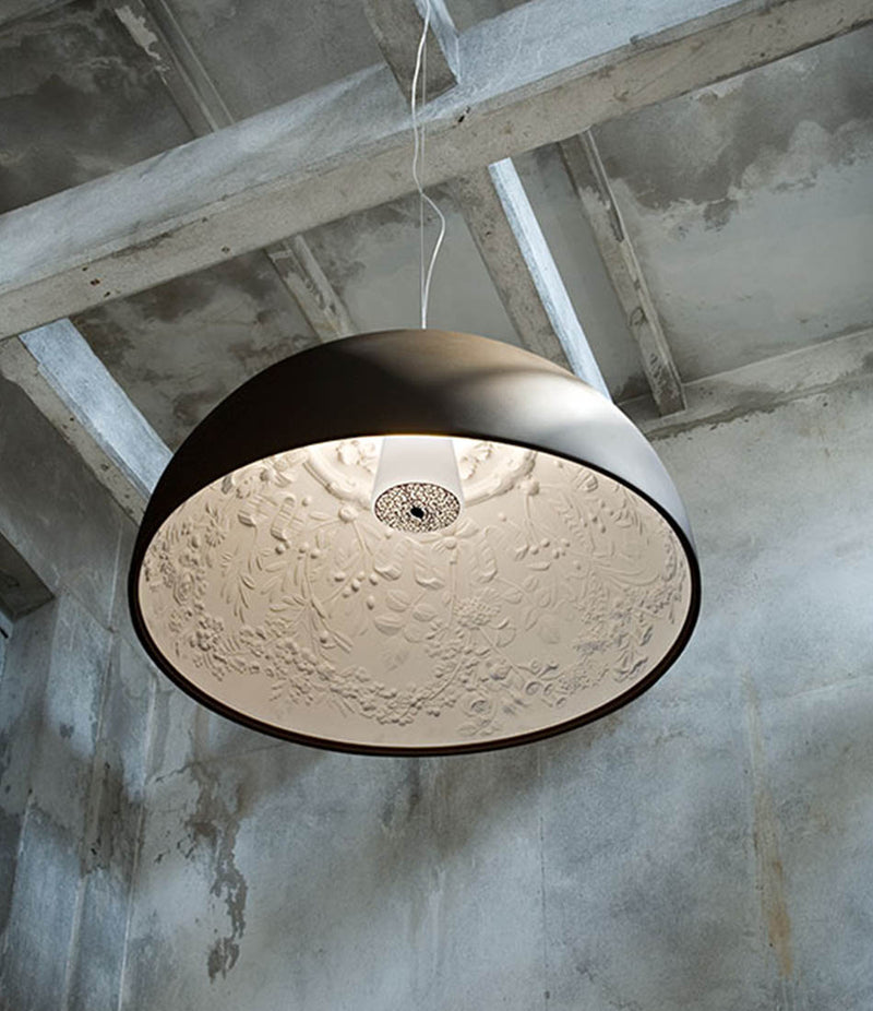 Flos Skygarden suspension lamp hanging from beams in a concrete room.